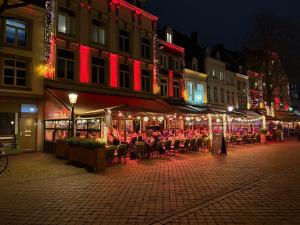 a group of people sitting at an outdoor restaurant at night at Maastricht Suites - City Studio A in Maastricht