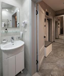 Un baño blanco con lavabo y espejo. en City Deluxe Apartments, en Tashkent