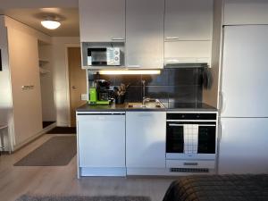 a kitchen with white cabinets and a sink and a microwave at Mimosa in Tampere