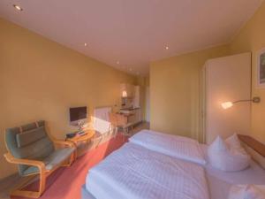 a bedroom with a bed and a chair and a television at Elegant eingerichtete Ferienwohnung in Granzow +22 photos