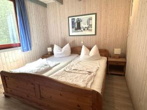 a bedroom with a large wooden bed with white pillows at exklusives skandinavisches Ferienhaus in Granzow