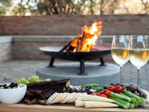 a table with a plate of food and two glasses of wine at Nzenga Lodge in Hoedspruit