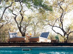 two chairs and a table next to a swimming pool at Nzenga Lodge in Hoedspruit +11 photos