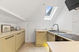 a kitchen with yellow cabinets and a sink and a window at Luxury modern 1 bed between Hampstead and Camden in London