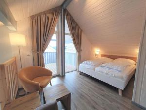 een slaapkamer met een bed, een stoel en een raam bij exklusives skandinavisches Ferienhaus in Granzow