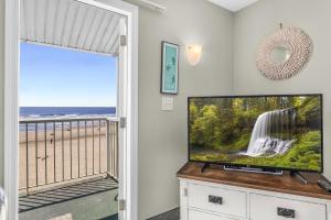 a living room with a tv and a balcony at Oceanfront Family Suite - Full Kitchen - Beach Access - Pool & Hot Tub in Lincoln City