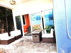 a porch with wicker chairs and a table and windows at Hilltop Villa Chez Coco in Rodney Bay Village
