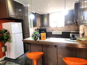 a kitchen with a white refrigerator and orange stools at Hilltop Villa Chez Coco in Rodney Bay Village