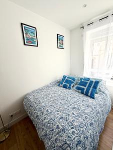 a bed with blue pillows in a white bedroom at Appartements meublés Brest centre in Brest