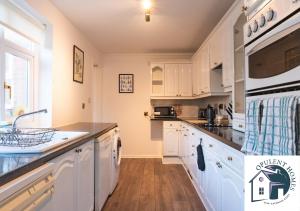 una cucina con mobili bianchi e ripiani neri di Detached 4 bed - Modern Contractor Pad - Reading a Caversham