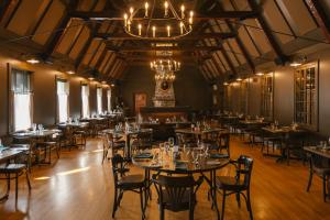 Un comedor con mesas y sillas y una lámpara de araña. en Gîte du Mont-Albert - Sepaq, en Sainte-Anne-des-Monts