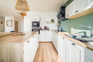 a kitchen with white cabinets and wooden floors at Appartement d’exception face au port de Quiberon in Quiberon +36 photos