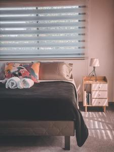 1 dormitorio con 1 cama con ventana y mesita de noche en Cabaña con vista al volcán, en Neltume