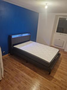 una cama en una habitación con una pared azul en Logement neuf 6 personnes ancienne ferme, en Censeau