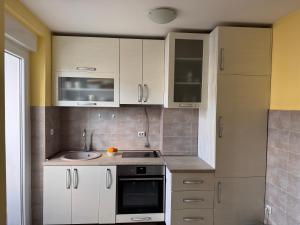 a kitchen with white cabinets and a sink at KMB suite in Nikšić