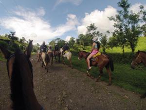eine Gruppe von Menschen, die auf einer unbefestigten Straße reiten in der Unterkunft Reserva Atmosfëre in Upala