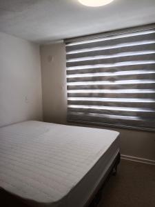 - une chambre avec un lit et une fenêtre avec des stores dans l'établissement Departamento hualpen, à Hualpen