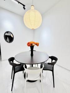 Una mesa con sillas y un jarrón con flores. en HeyMono #JPO #Senai Airport #IOI mall #Landed #Netflix, en Kampong Saleng