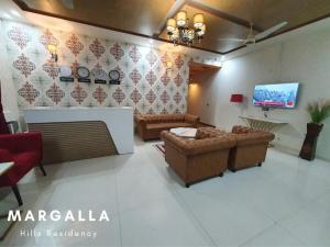 a living room with couches and a flat screen tv at Margalla Residency Islamabad in Islamabad +15 photos