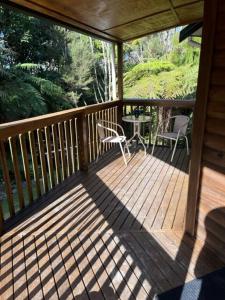 een houten veranda met een tafel en stoelen erop bij Fern Cottage in Mangonui