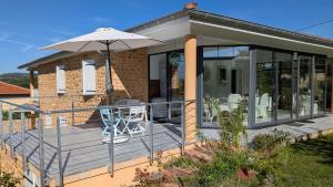 a house with a deck with an umbrella at Alix au pays des Pierres Dorées in Alix