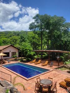 une piscine avec une table, des chaises et des arbres dans l'établissement Hotel Selva Montana, à San Lorenzo