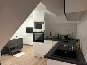 a white kitchen with a sink and a microwave at Appartement Douceur in Horbourg