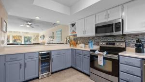 a kitchen with white cabinets and black appliances at Easy Breezy - Lakefront for 6 in Sunrise Beach