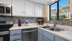 a kitchen with white cabinets and a sink and a window at Easy Breezy - Lakefront for 6 in Sunrise Beach