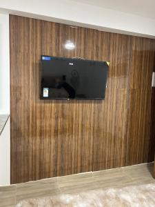 TV de pantalla plana en una pared de madera en Entre Mar e Morros, Apto praia Pontal Recreio, en Río de Janeiro