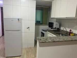 cocina blanca con nevera y fregadero en Entre Mar e Morros, Apto praia Pontal Recreio, en Río de Janeiro 6 fotos más