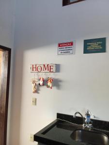 a kitchen with a sink and a home sign on the wall at Hostel pousada floresta in Joinville