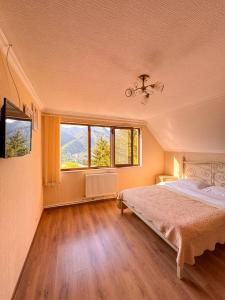 Hidden Forest Cottage في بورجومي: غرفة نوم بها سرير ونافذتين