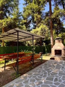 Hidden Forest Cottage في بورجومي: مقعد خشبي تحت مظلة بجوار فرن حجري