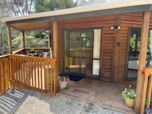 een houten hut met grote glazen deuren op een dek bij Fern Cottage in Mangonui