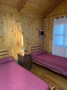 due letti in una stanza con pareti in legno di Olivillos II a Balneario Pehuén-Có