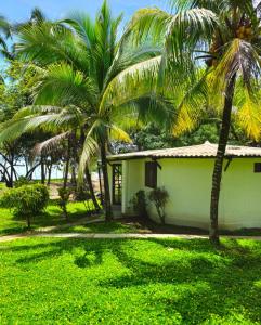 a white house with palm trees in front of it at Bio-Cébaco Cabañas in Isla Cebaco 