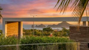 a building with a view of the ocean at sunset at Modern Condo with Stunning Bay Views in Cabo San Lucas