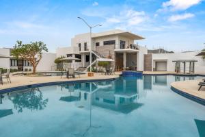 a swimming pool in front of a house at Modern Condo with Stunning Bay Views in Cabo San Lucas