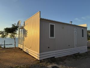 a tiny house with a yellow facade next to the ocean at Adriastay 360 in Klenovica