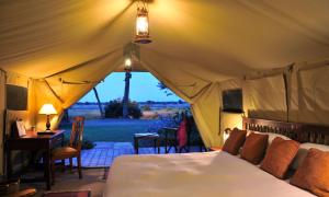 ein Schlafzimmer mit einem Bett in einem Zelt mit Aussicht in der Unterkunft Sweetwaters Serena Camp in Nanyuki