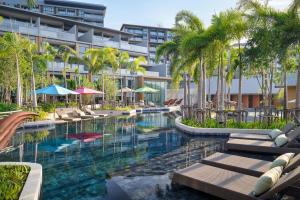 a resort pool with chairs and palm trees and a building at Private Villa at Mida Grande Resort in Surin Beach