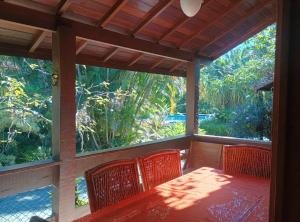 a screened in porch with a table and chairs at Camburizinho Casa em condomínio a 250m da praia in São Sebastião
