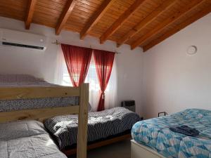 a bedroom with two beds and a window with red curtains at Nat depto in Senillosa
