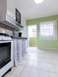 eine Küche mit grünen Wänden und weißen Fliesenböden in der Unterkunft Casinha p/5 Charmosa in Volta Redonda