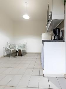 eine Küche mit einem Tisch und Stühlen sowie einem weißen Boden in der Unterkunft Casinha p/5 Charmosa in Volta Redonda