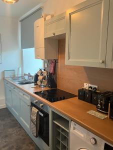 Toll House في ويك: مطبخ بخزائن بيضاء وفرن موقد