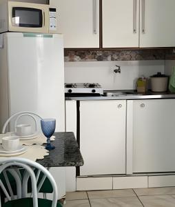 een keuken met witte kasten, een tafel en een magnetron bij Studio p/3 Climatizado in Volta Redonda