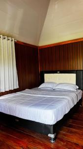 ein großes Bett in einem Schlafzimmer mit Holzvertäfelung in der Unterkunft The Mawun Lombok in Selong Belanak