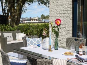 un tavolo con un fiore in un vaso su un patio di Relaxing Waterfront Bungalow a Nieuw-Loosdrecht